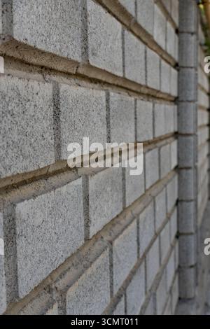 Close-up of light gray brick wall with rough texture and dark mortar joints in a running bond pattern, ideal for backgrounds, architecture, and design Stock Photo