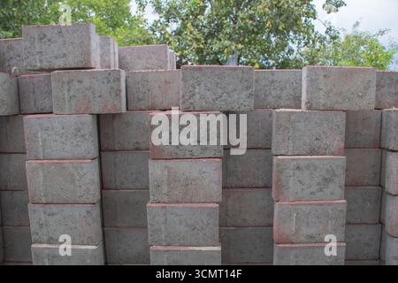 Stack of concrete bricks arranged in rows outdoors, construction material background for building industry, architecture and infrastructure projects Stock Photo