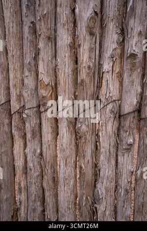 wooden fence created with small tree trunks wrapped in or tied together with wire grunge textured bark of tree natural product backdrop background wal Stock Photo