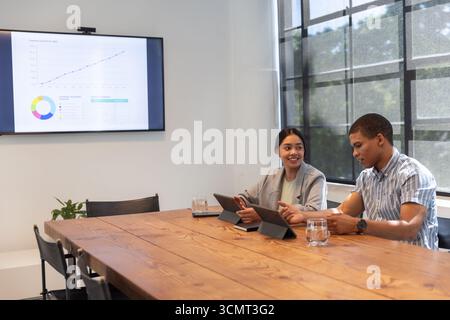 Diverse coworkers analyzing charts, interacting with tablets in boardroom, copy space Stock Photo