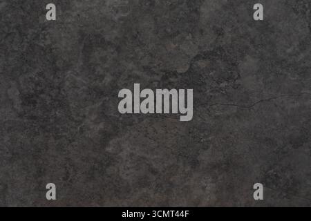 Dark textured surface with subtle patterns and a crack highlights the beauty of natural stone material in a close-up view Stock Photo