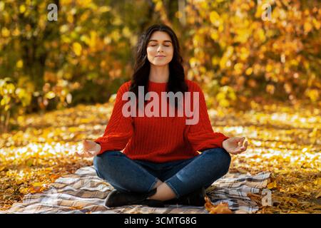 Concentrated young woman meditating in beautiful autumn park Stock Photo