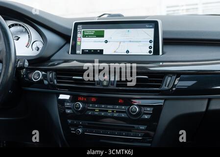 Google maps navigation on screen in modern car. BMW car interior - close-up shot of infotainment system with Carplay screencast. Stock Photo