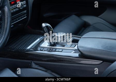 Automatic gear selector in luxury car. Automobile interior in dark tones, bottom part of center console with lots of buttons. Stock Photo