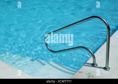 Water in swimming pool rippled water detail background. Water in swimming pool with sun reflection. Blue swimming pool rippled water detail. Stock Photo