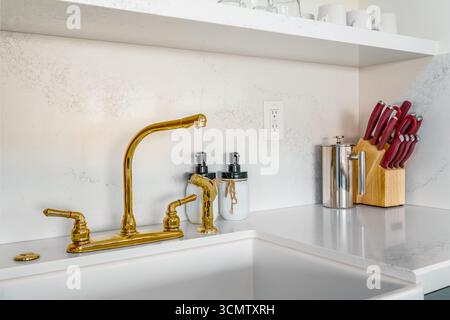 Bright modern kitchen corner with sink gold faucet and white marble countertop Stock Photo