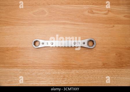 This is an example of a used 6-point 5/8" and 11/16" Snap-on ratcheting box wrench on a wooden table.  Reverse side is viewed here. Stock Photo