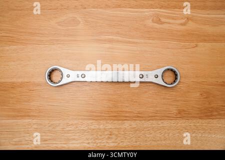 This is an example of a used 12-point 7/8" and 15/16" Snap-on ratcheting box wrench on a wooden table.  Reverse side is viewed here. Stock Photo
