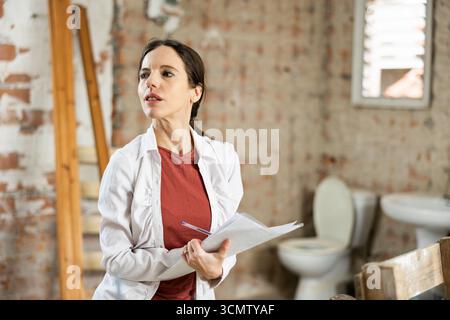 Interested brunette making notes while planning home renovation Stock Photo
