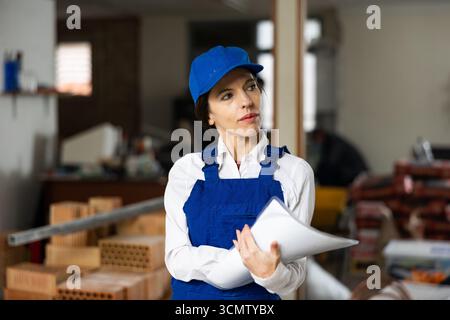 Female designer making checklist while planning building overhaul Stock Photo