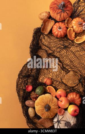 Halloween frame with party decorations of pumpkins, bats, spiders on orange background from above. Happy halloween card in flat lay style. Stock Photo