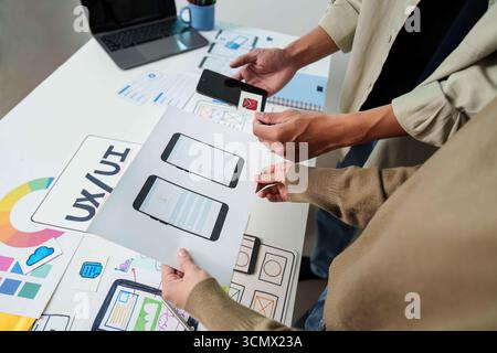 UX UI Prototyping Session. Team creating mobile interface designs and discussing concepts. Stock Photo