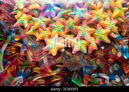 Close up of colorful gummy star candies with jelly worms. Sweet background for candy shop, party, kids celebration, holiday or creative food design. Stock Photo