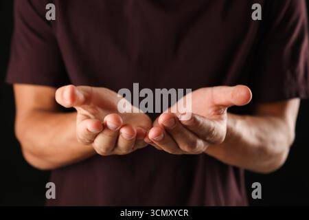 Man holding something on black background, closeup Stock Photo