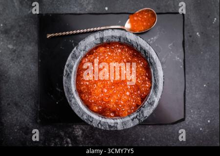 Exquisite salmon roe, vibrant and rich, ideal for adding a touch of elegance to your culinary creations. black background. top view. Stock Photo