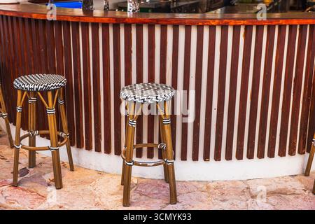 Close up view of two high bar stools with woven seats standing by wooden counter in tropical restaurant bar. Curacao. Stock Photo