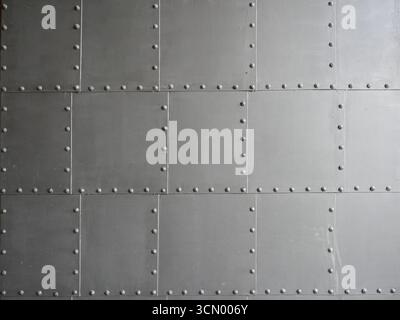 Gray metal plates with rivets, matte and aged. Surface of an old door with light shadow. Copyspace. Stock Photo