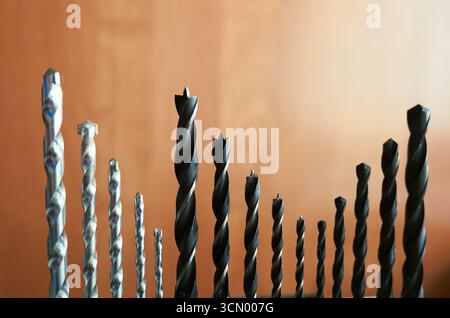 Various drill bits for wood and metal arranged in a row, showing different sizes and types of tools for construction and repair work. Stock Photo