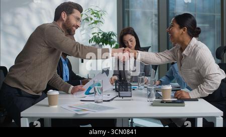 Caucasian business woman team leader showing graph chart talking briefing two multiethnic businesspeople shake hands handshaking gesture men women Stock Photo