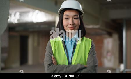 Confident successful Korean Japanese woman crossed arms posing looking at camera portrait female builder developer businesswoman business Chinese Stock Photo