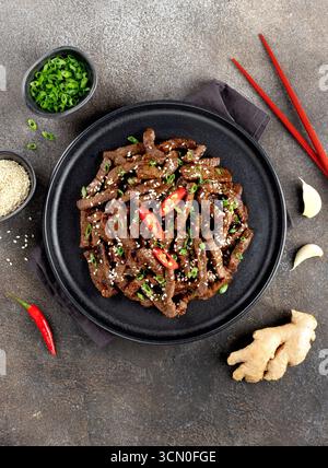 Asian teriyaki beef strips with spice, sesame on a gray background. Top view. Asian food. Stock Photo
