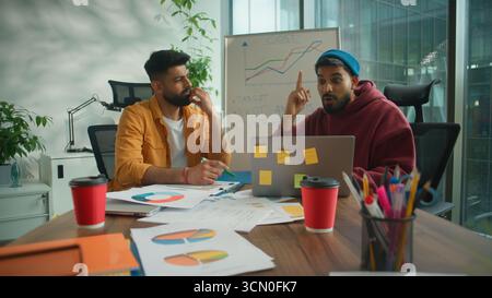 Pensive thinking two Arabian guys males Hindu business men with laptop think solution come up with idea decision online insight in informal office Stock Photo