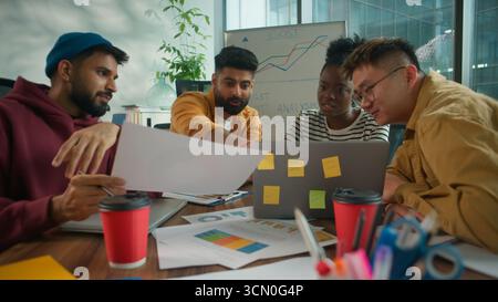 Focused concentrated informal casual startup business team considering paper document report information together talking solving finance problem Stock Photo