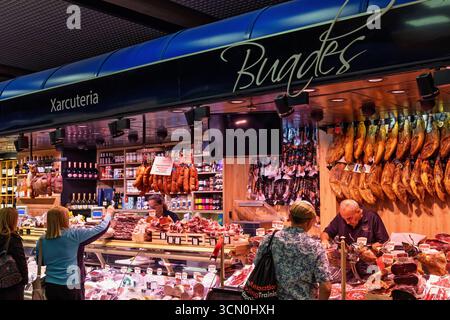Customers by a charcuterie in a market hall Stock Photo