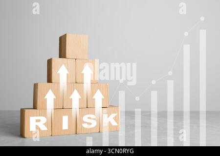 Pyramid of wooden cubes with word Risk and arrows on table Stock Photo