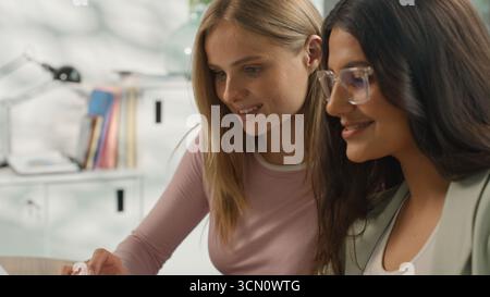 Two positive multiethnic business women teamwork cooperation informal team in office communicate discuss diversity businesswomen girls females Stock Photo