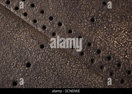 Detailed view of a textured rusty metal surface with punched holes, showcasing weathered industrial patterns. Ideal for backgrounds, industrial themes Stock Photo