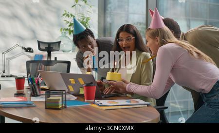 Indian businesswoman Arabian woman working laptop in office three multiracial business colleagues make surprise celebrating congratulate with birthday Stock Photo