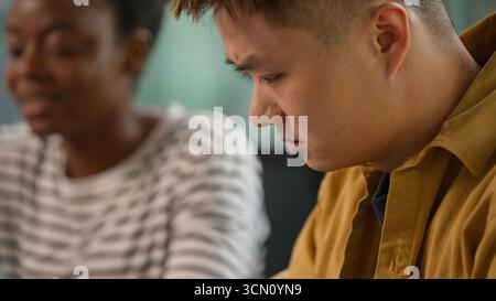 Asian concentrated businessman Korean business man using digital tablet device gadget online browsing talking serious with African American Stock Photo