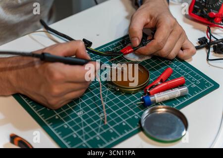 Hands working with soldering iron and wires for electronic repair Stock Photo