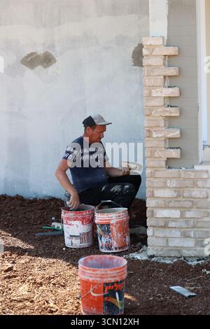 A man working on a brick wall at a construction site Stock Photo