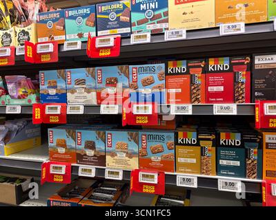 Various brands of protein and healthy snack bars like Clif, Kind, and Builders are displayed on a supermarket shelf, featuring promotional "Price Drop Stock Photo