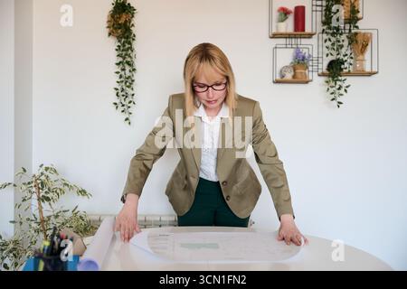 Woman architect analyzing blueprint for building design Stock Photo