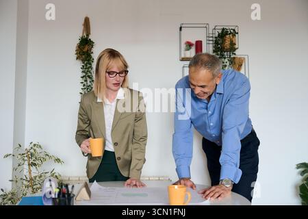 Business colleagues reviewing blueprint for project planning Stock Photo