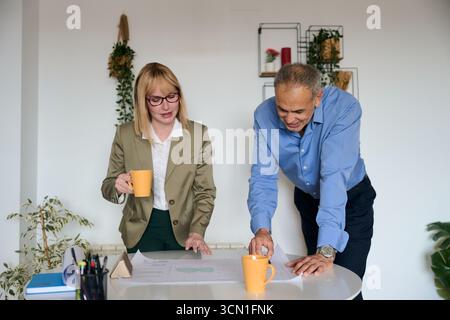 Business colleagues reviewing blueprint during office meeting Stock Photo
