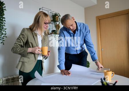 Architects collaborating on building plans in office Stock Photo