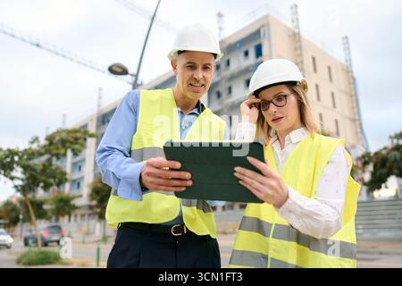 Engineers discussing construction project plans using digital tablet Stock Photo