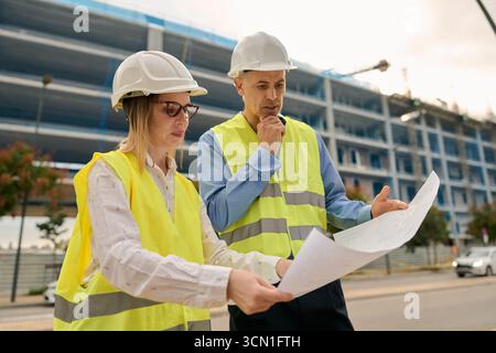 Architects and engineers discussing blueprint at construction site Stock Photo