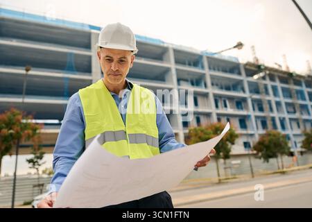 Male engineer reviewing blueprints at construction site Stock Photo