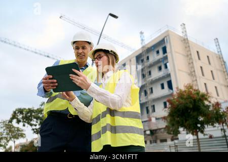 Engineers collaborating on construction site using tablet Stock Photo