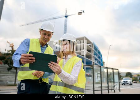 Engineers discussing construction project plans using tablet Stock Photo