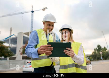 Engineers discussing construction plans using digital tablet Stock Photo