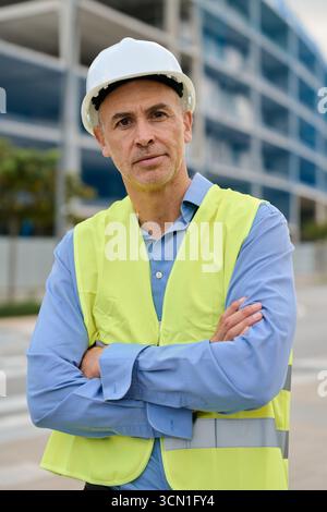 Construction engineer wearing hard hat standing at building site Stock Photo