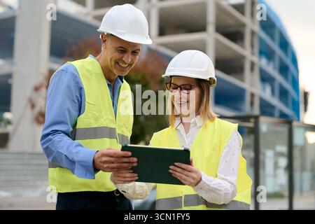 Construction engineers collaborating on building site with tablet Stock Photo