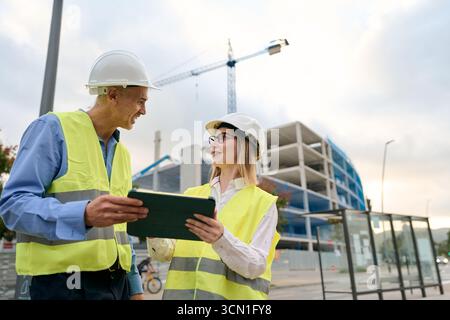 Engineers discussing building plans using digital tablet Stock Photo