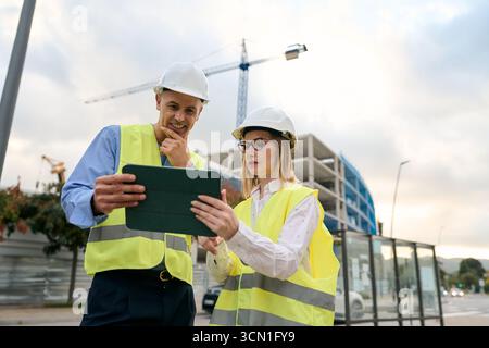 Engineers reviewing construction plans on digital tablet Stock Photo